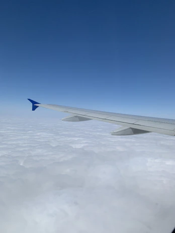 An aerial view of a commercial airplane soaring above fluffy white clouds.