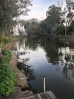Picturesque river scene in Ibirité with calm water reflecting surrounding trees and houses.