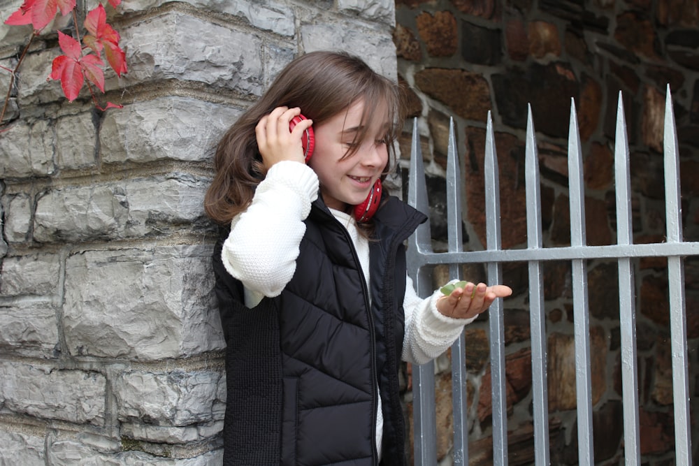 woman in black vest and white coat standing beside brown metal fence