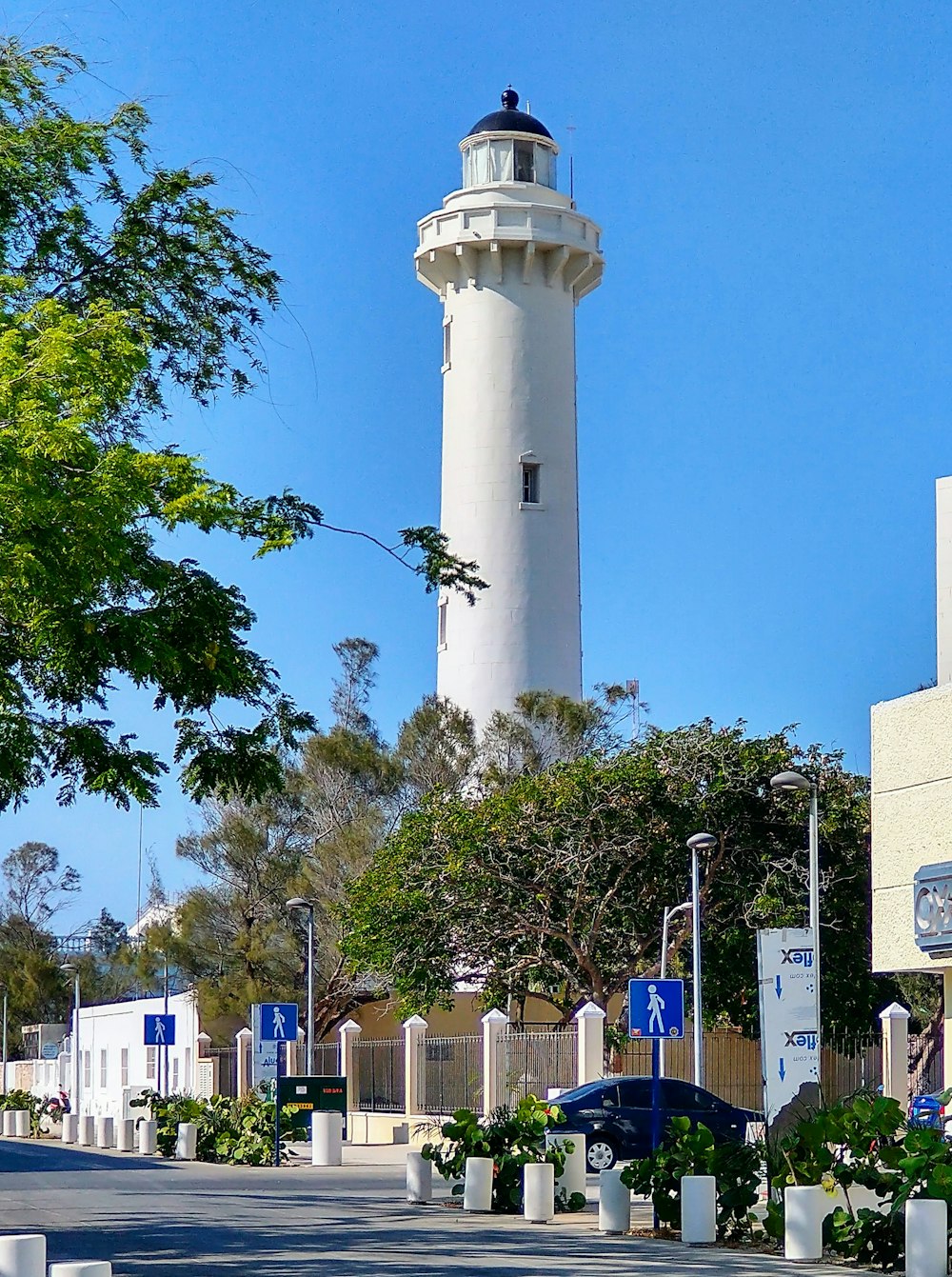 white concrete tower near green trees during daytime