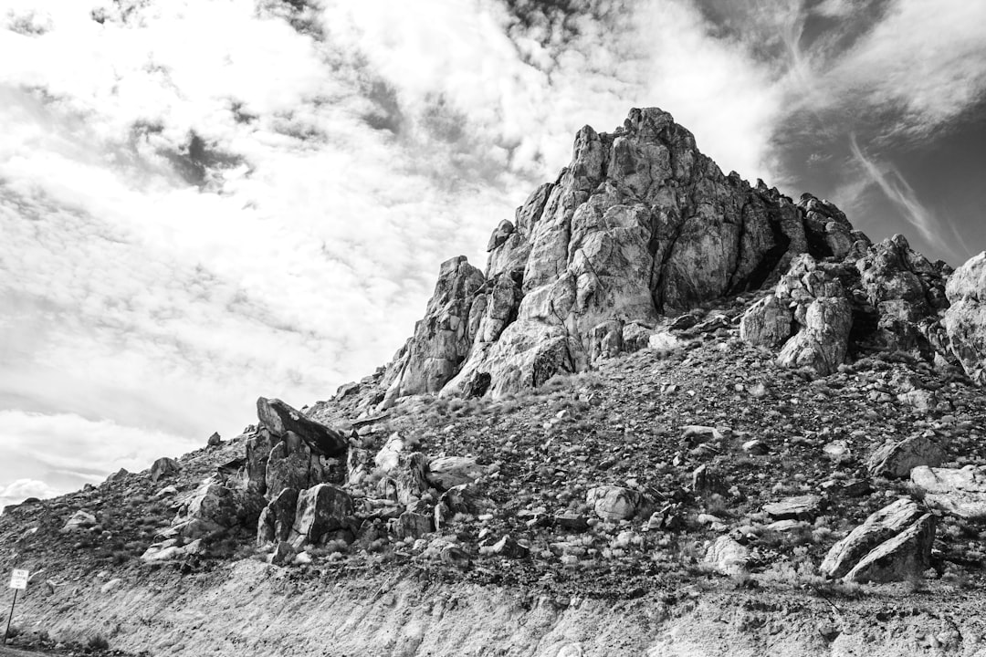 grayscale photo of rocky mountain under cloudy sky