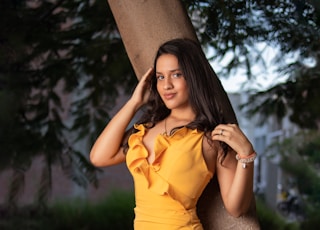 woman in yellow dress sitting on tree trunk