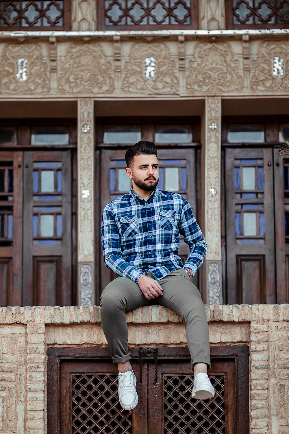Uomo in camicia a quadri blu e bianca e pantaloni grigi seduto sul muro di  mattoni marrone foto – Kashan Immagine gratuita su Unsplash
