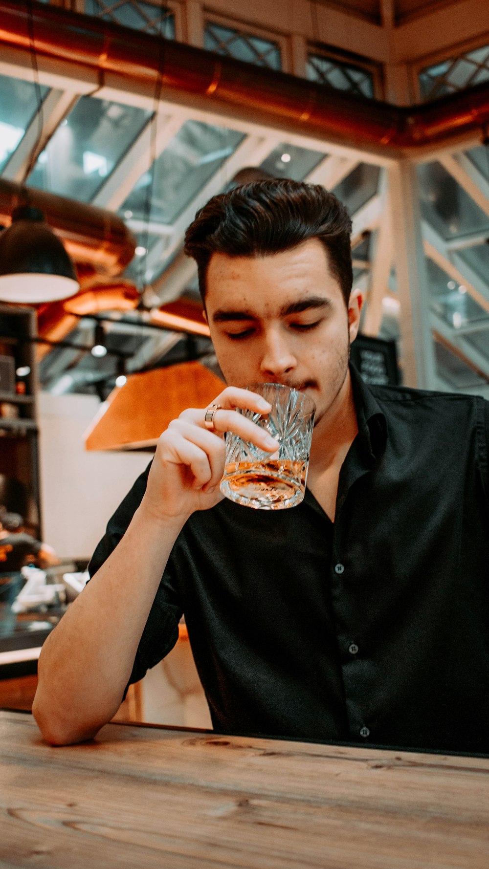 man in black button up shirt drinking from clear drinking glass