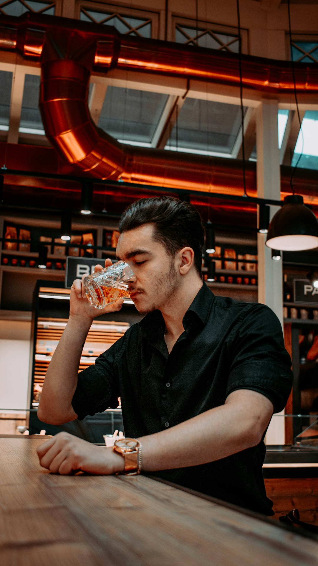 man in black polo shirt drinking from clear drinking glass