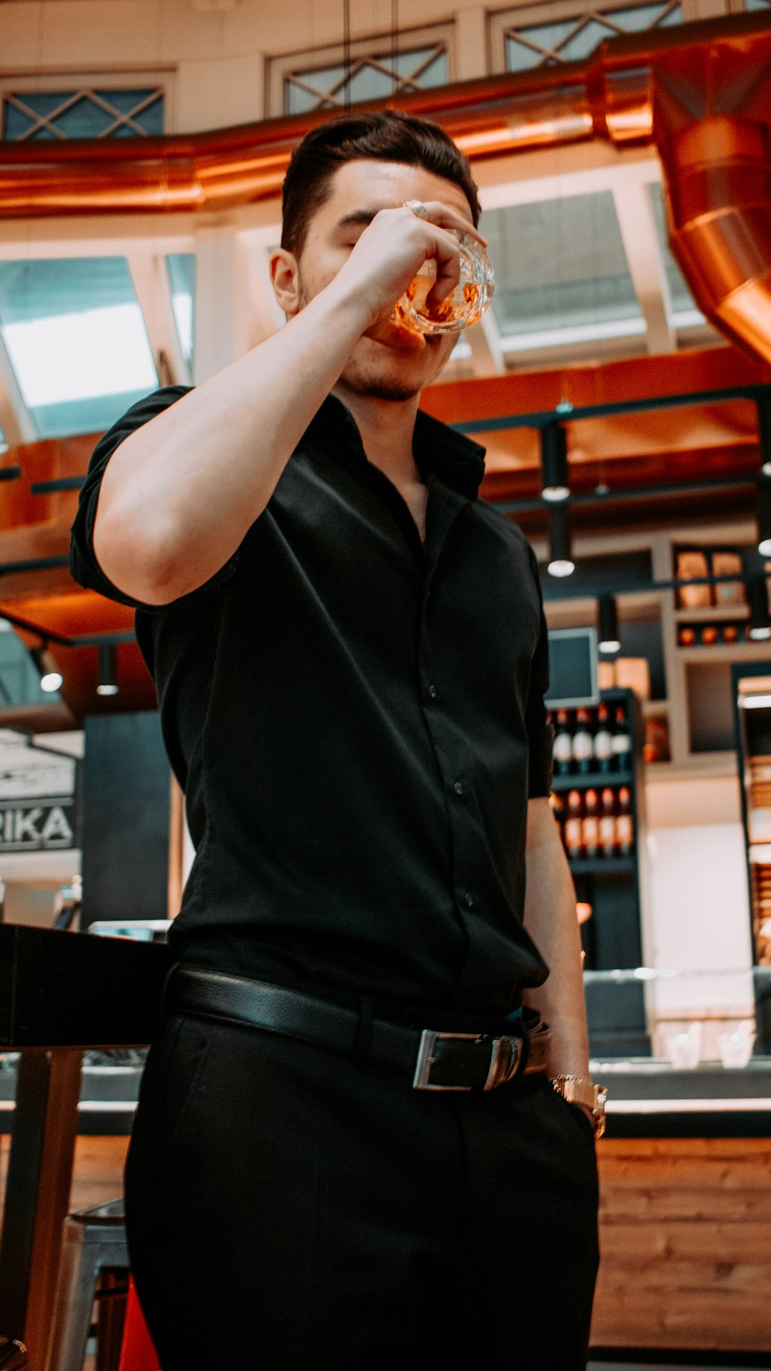 man in black polo shirt drinking from clear drinking glass