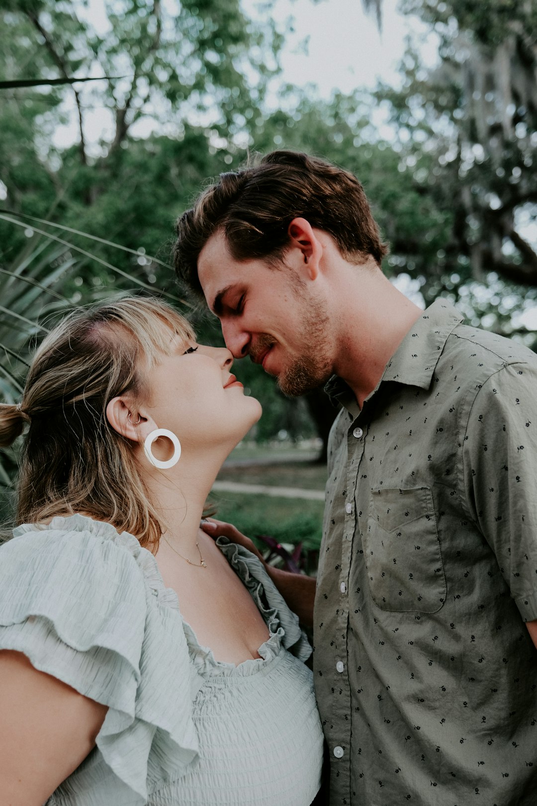 man in gray button up shirt kissing woman in white tank top during daytime