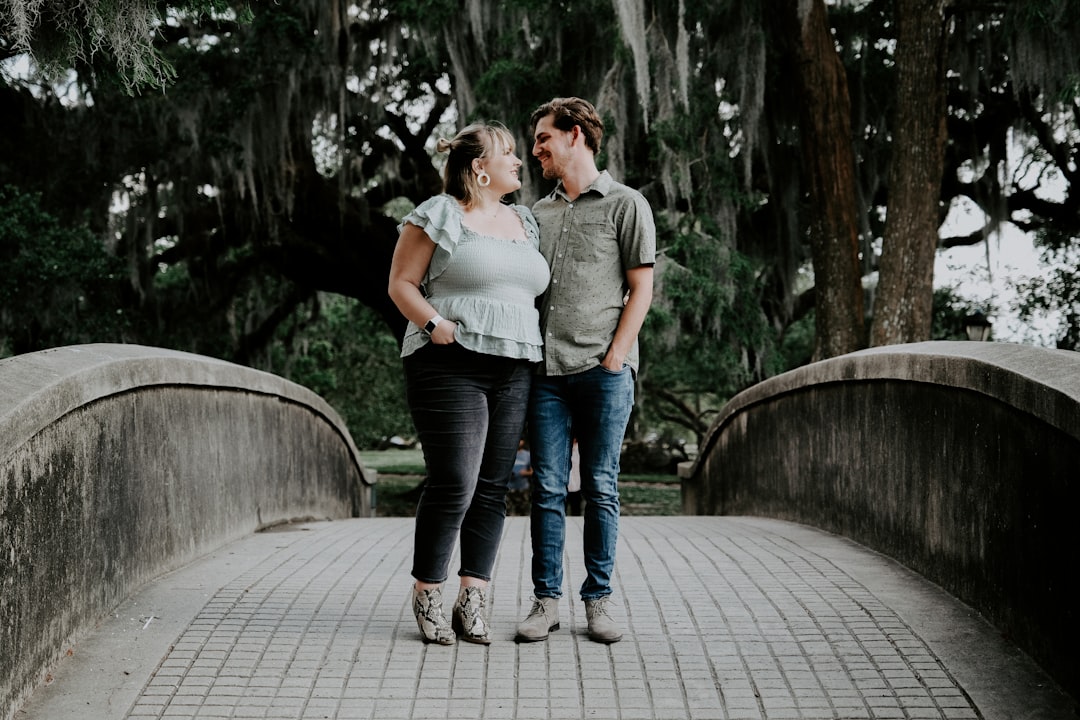 man and woman kissing on brown wooden bridge during daytime