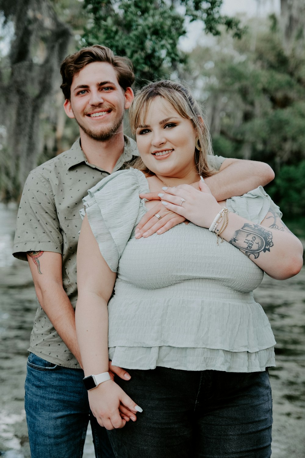 man in gray button up shirt hugging woman in white dress