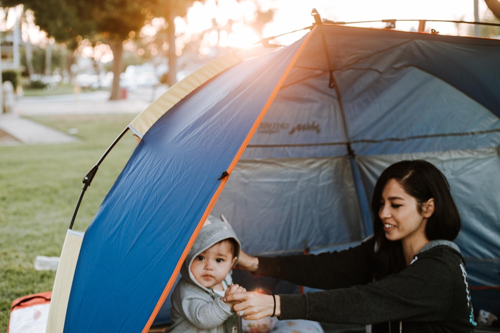 woman in black long sleeve shirt sitting beside blue tent during daytime