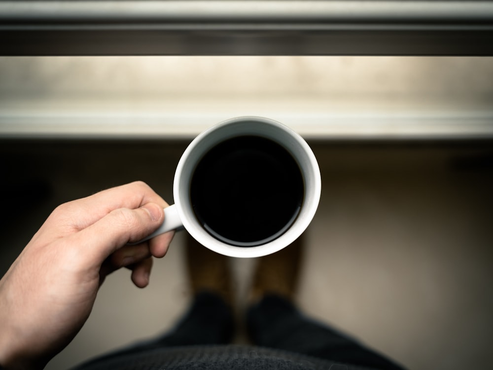 person holding white ceramic mug