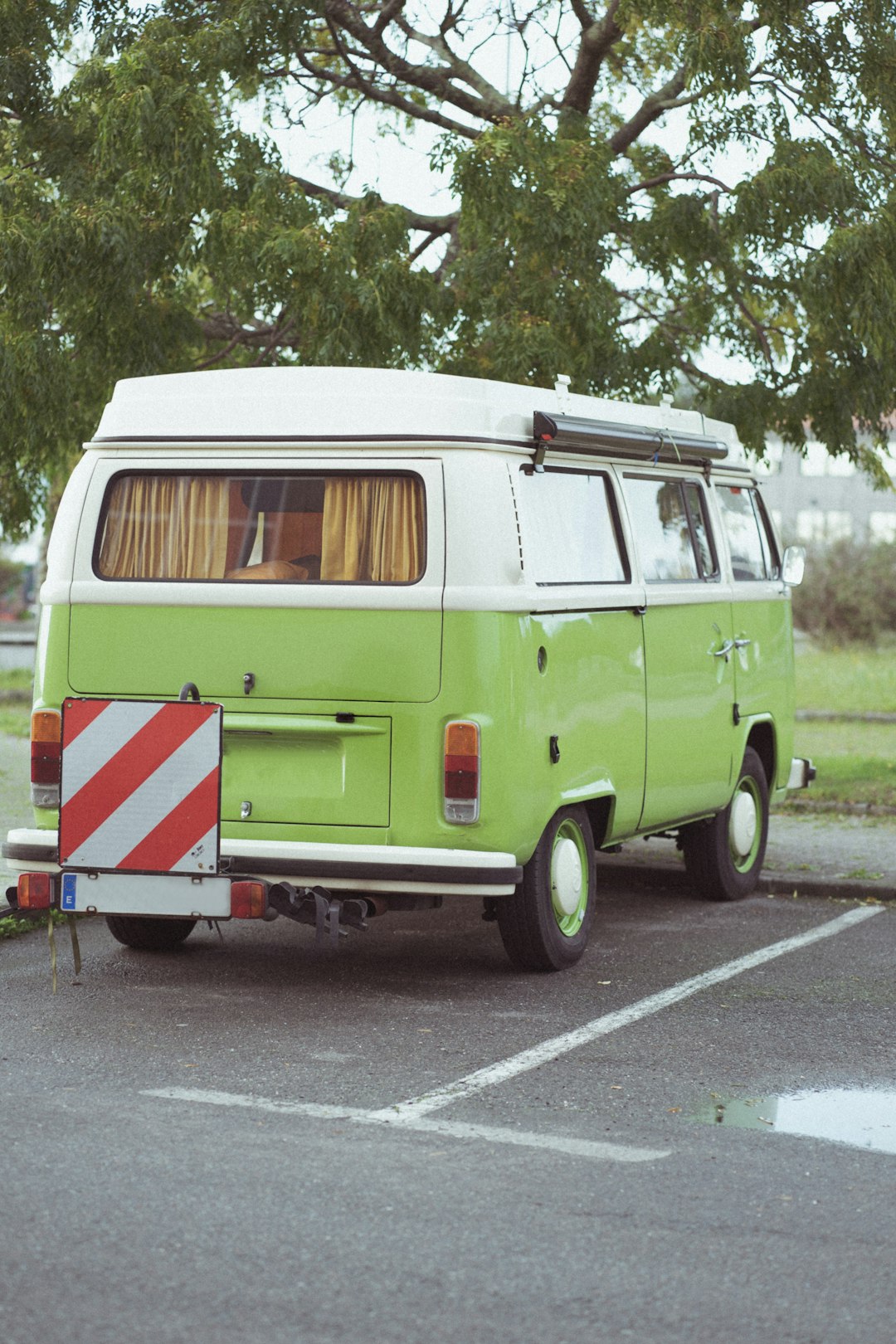 green and white volkswagen t-2 parked on gray asphalt road during daytime