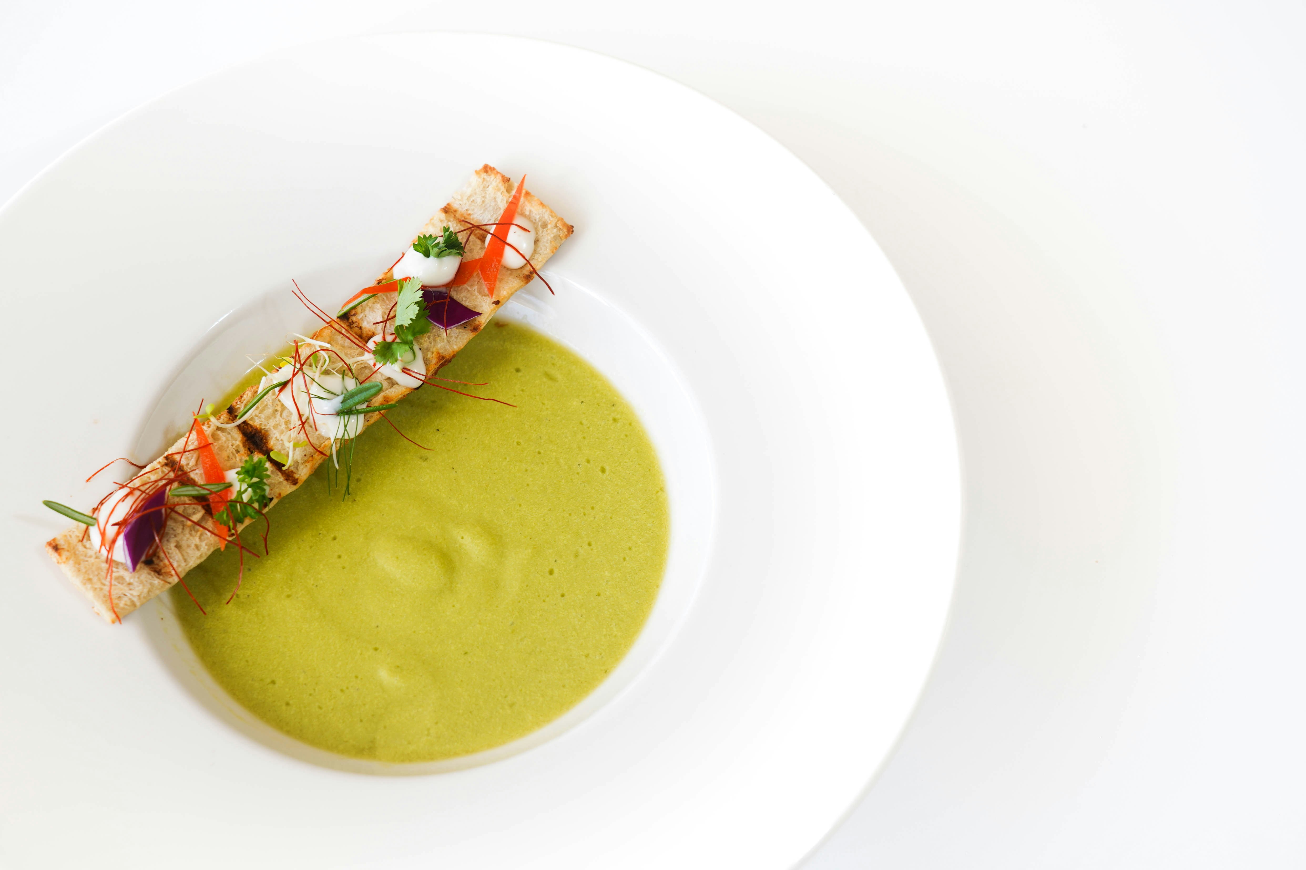 brown soup with green leaf on white ceramic plate