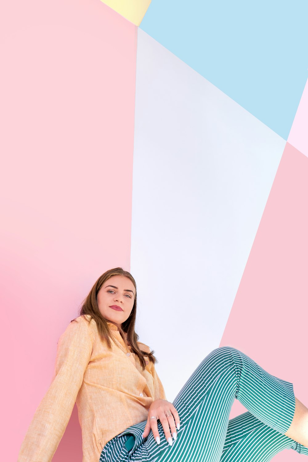 woman in brown long sleeve shirt sitting on blue and white striped chair