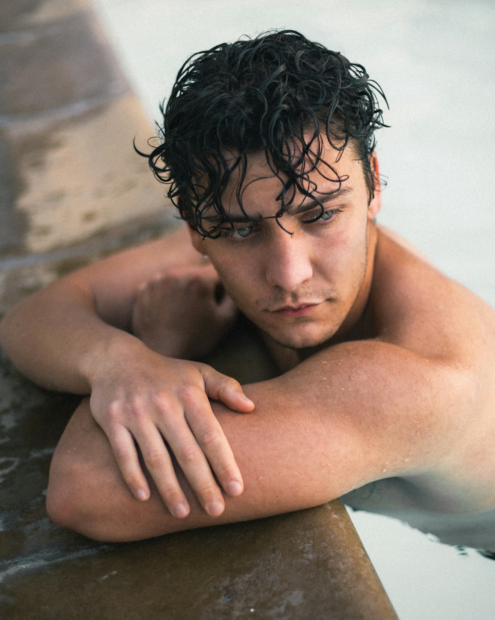 topless man lying on brown concrete surface