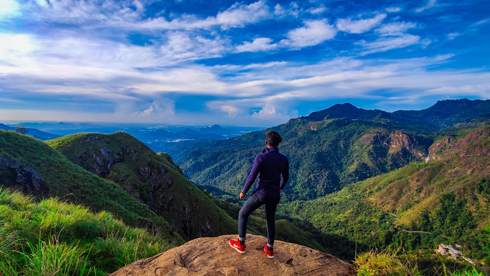 woman in black long sleeve shirt and blue denim jeans standing on brown rock mountain during