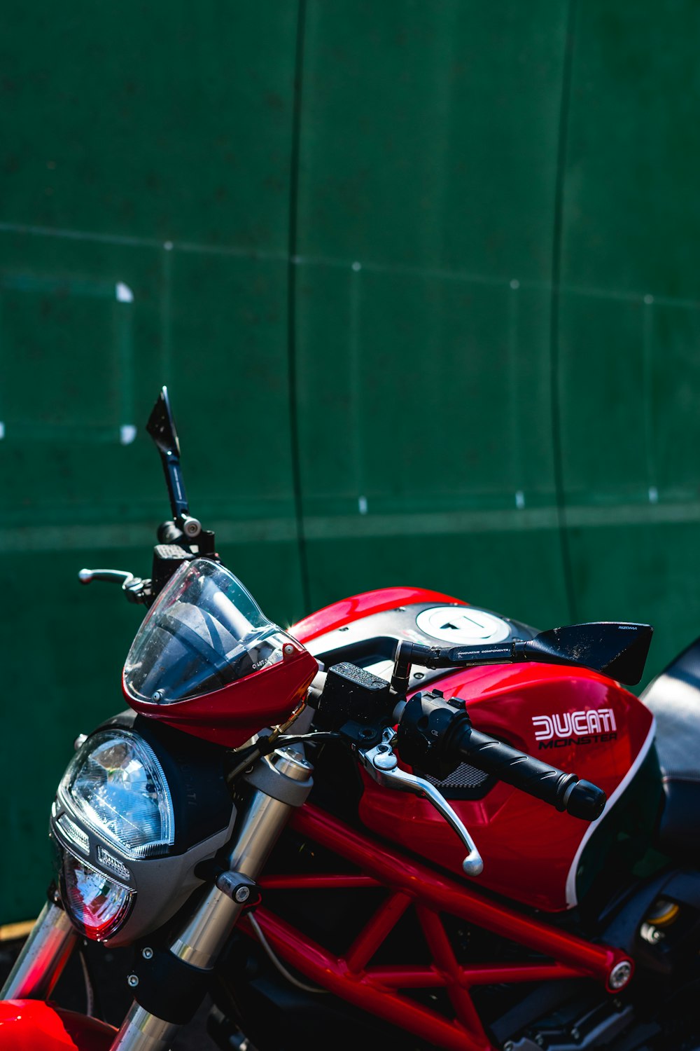 a red motorcycle parked in front of a green wall