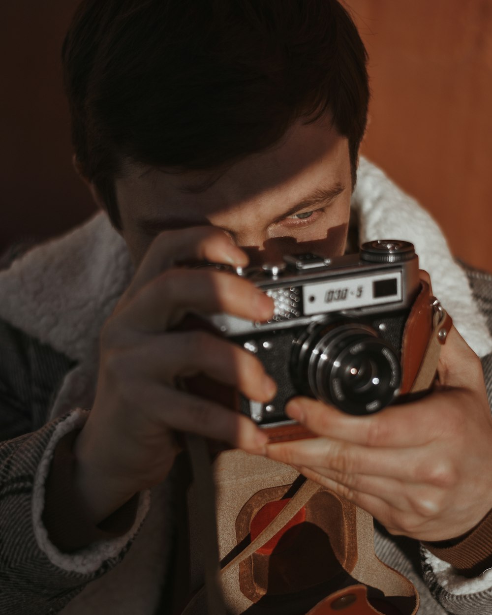 man in gray sweater holding black and silver camera