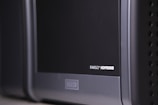 A close-up view of a black and gray electronic device, with the label 'FARGO HDP5000' visible on its surface. The device features a sleek design with rounded edges and some ventilation holes on the side.