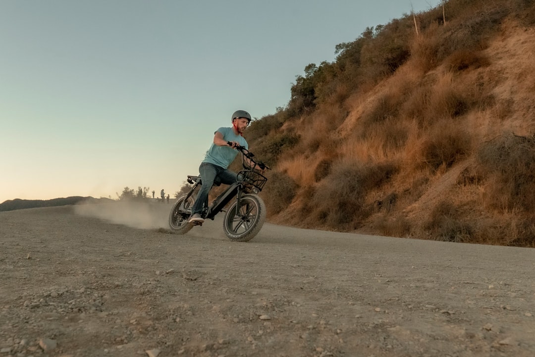 man riding motocross dirt bike on gray sand during daytime