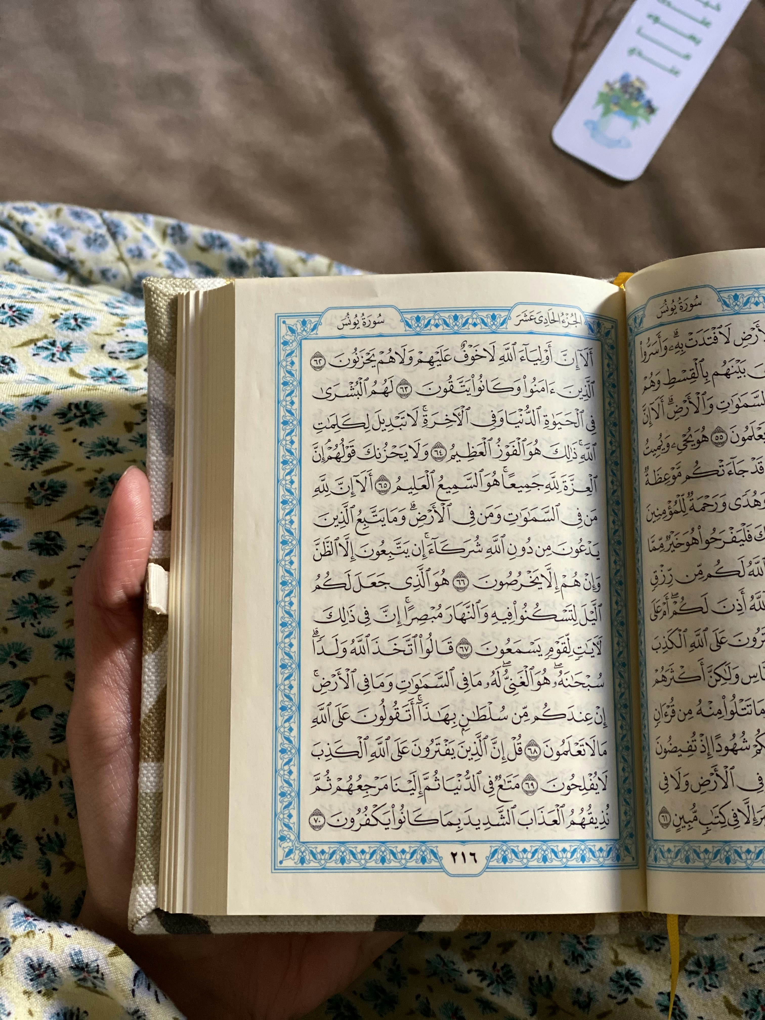 A smiling woman holding a beautifully designed custom Quran with green and orange accents.