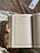 A smiling woman holding a beautifully designed custom Quran with green and orange accents.
