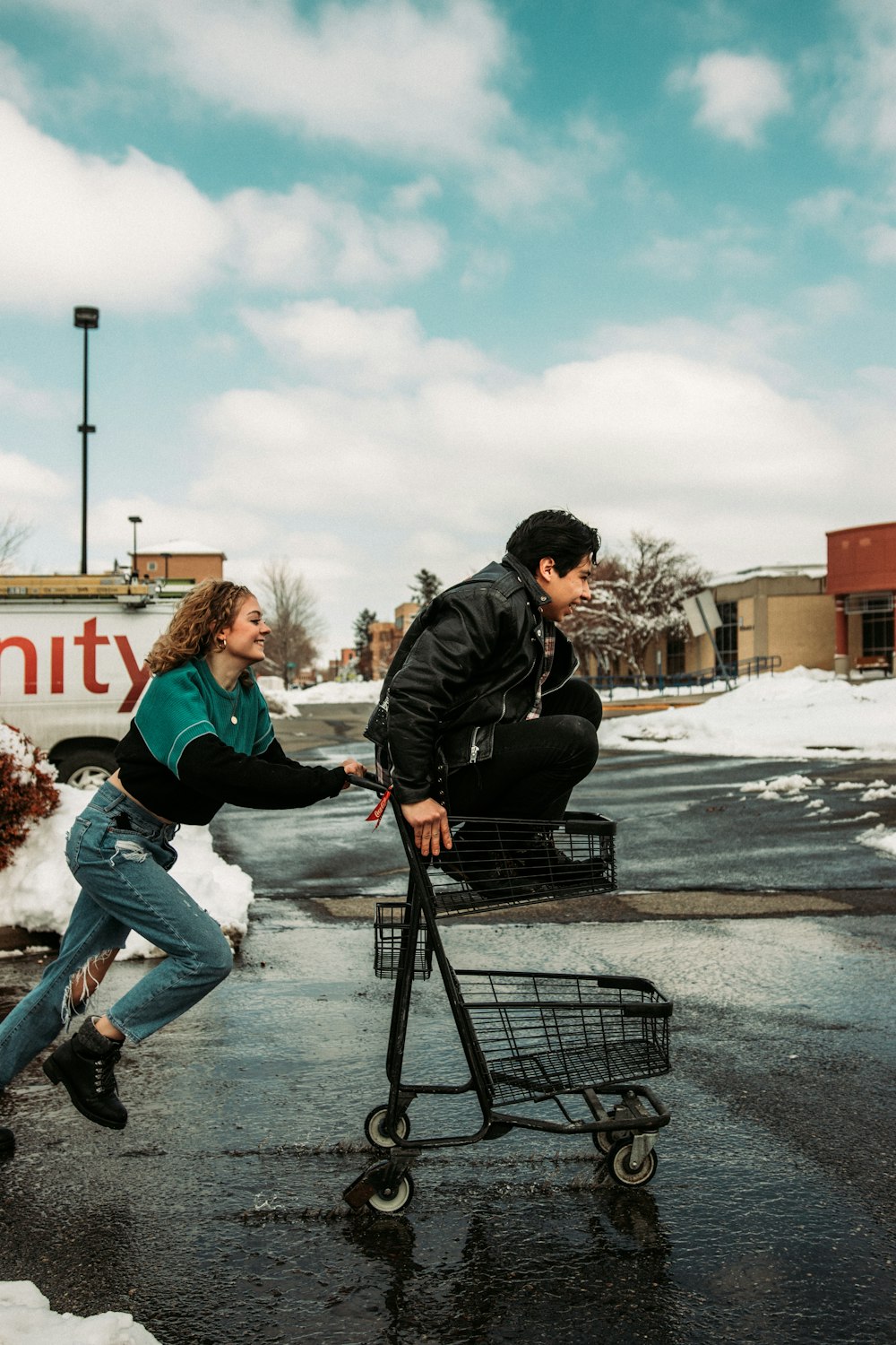 man in black jacket and woman in white jacket riding on black shopping cart during daytime