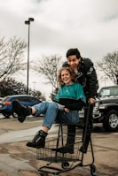 man and woman sitting on shopping cart