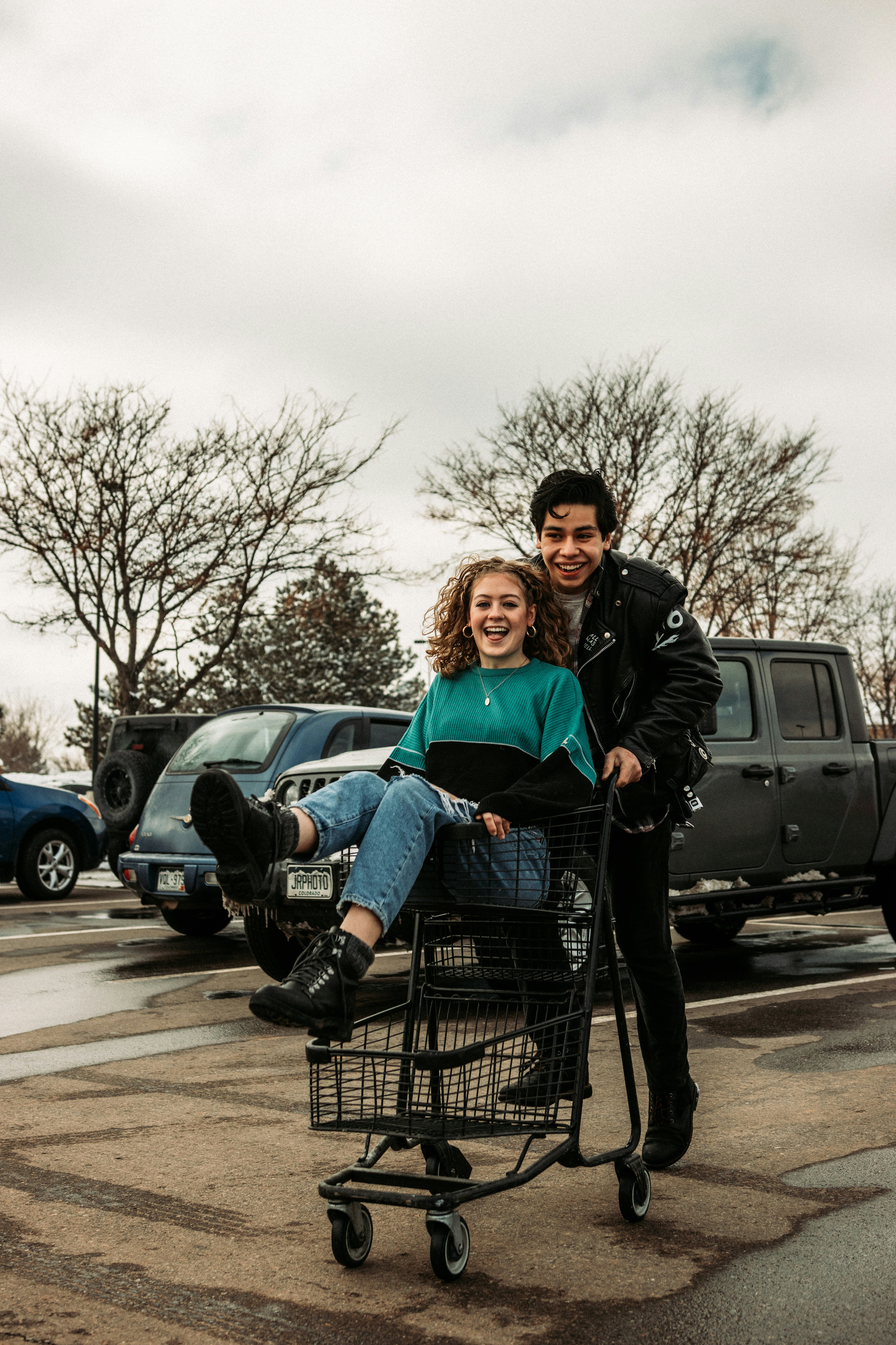 man and woman sitting on black metal shopping cart during daytime