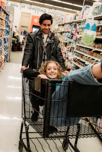 A smiling family shopping together with various everyday products in their cart.
