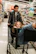 A smiling man checking out at Sam's Club with a cart loaded with party supplies.