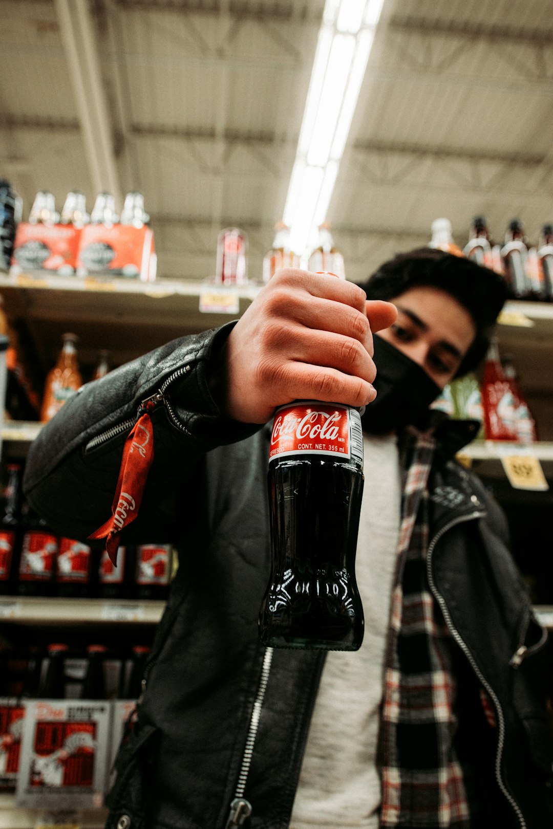 man in black leather jacket holding coca cola bottle