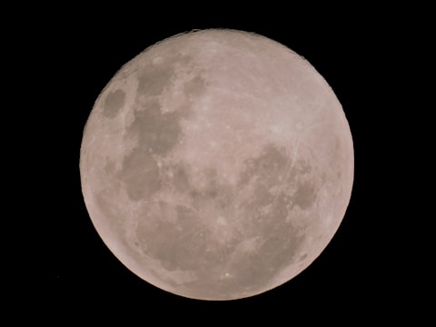 A clear and detailed view of a full moon with craters and surface features visible against a stark black background.
