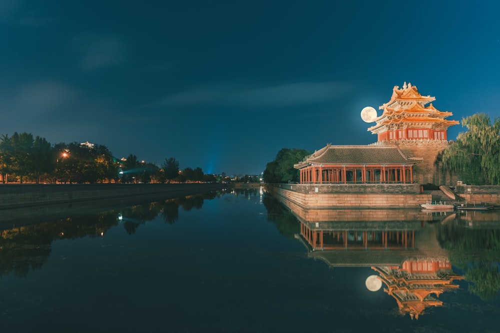 brown and white temple near body of water during night time