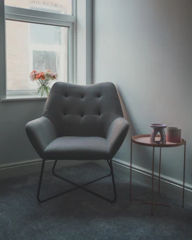 A softly lit corner with a terracotta candle, dried florals in a ceramic vase, and a textured linen throw draped over a cozy armchair.