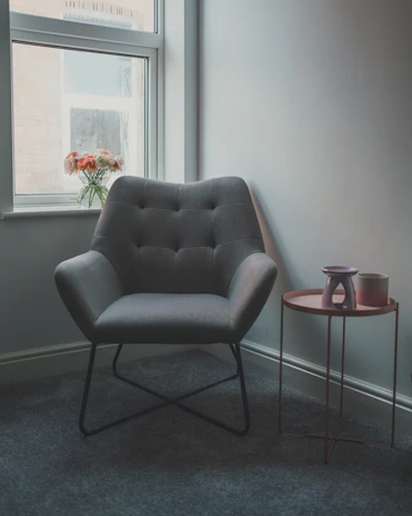 A cozy corner with a red velvet armchair, a vase with seasonal flowers, and a glowing candelabrum.