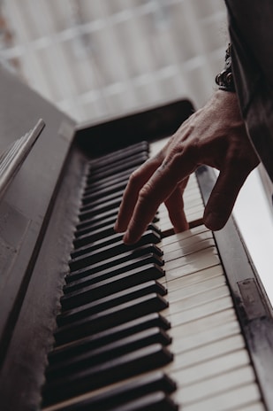 Artist playing the piano captured from a side angle, highlighting hand movement.