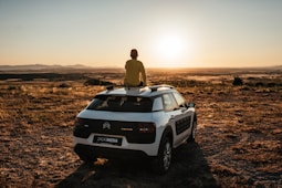 hombre sentado en un citroen c4 en el amanecer