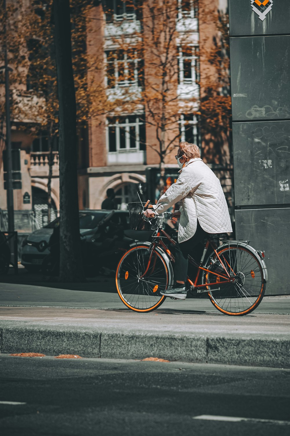 man in white suit riding red city bicycle on road during daytime