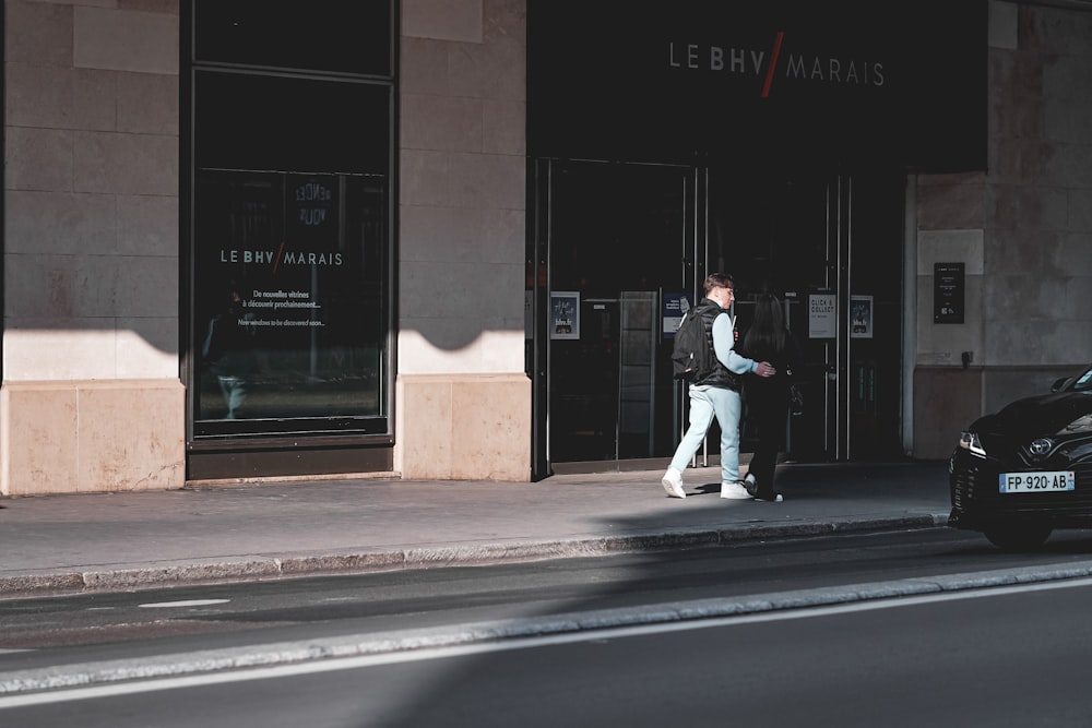 man in white shirt and pants walking on sidewalk during night time