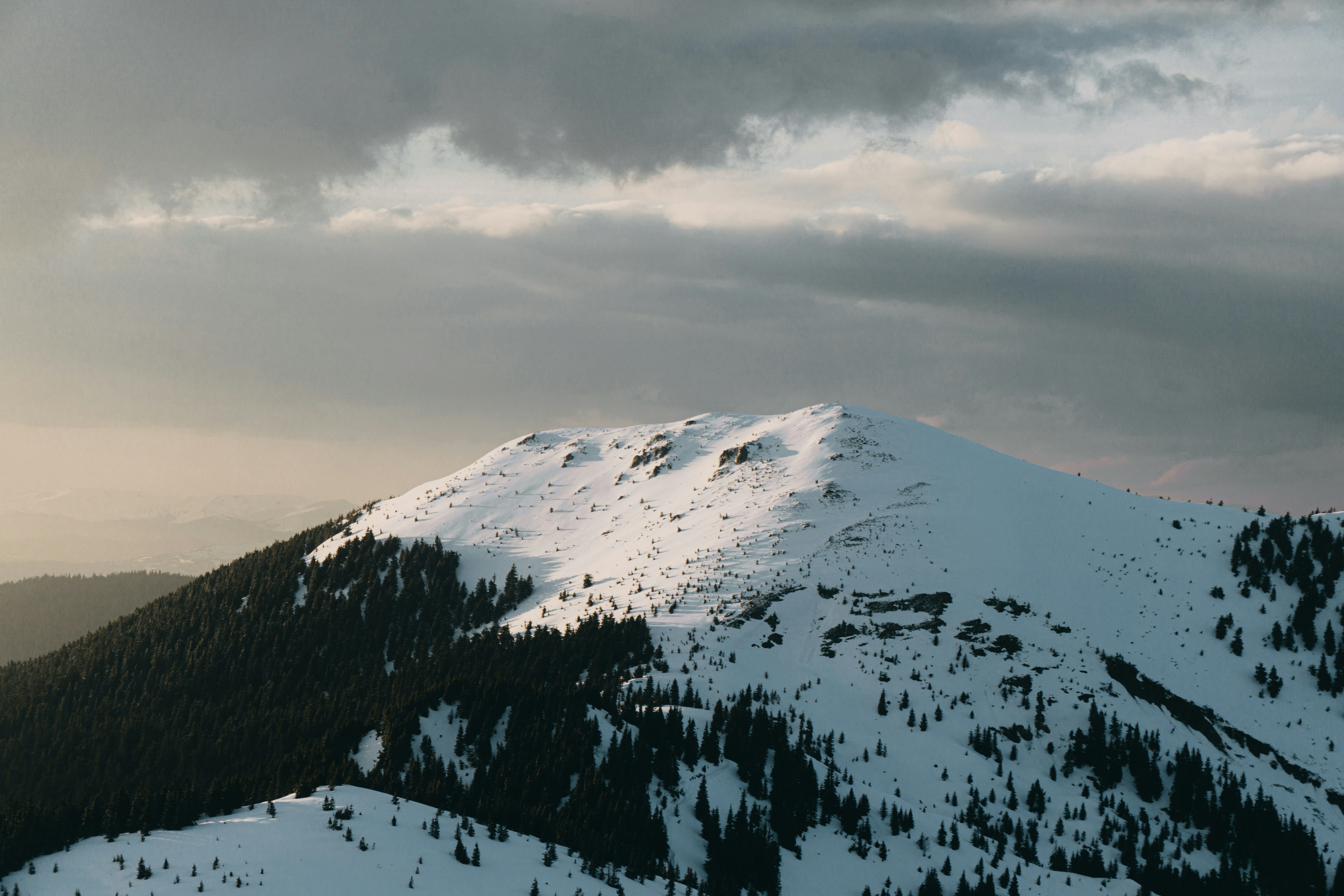 snow covered mountain under cloudy sky during daytime