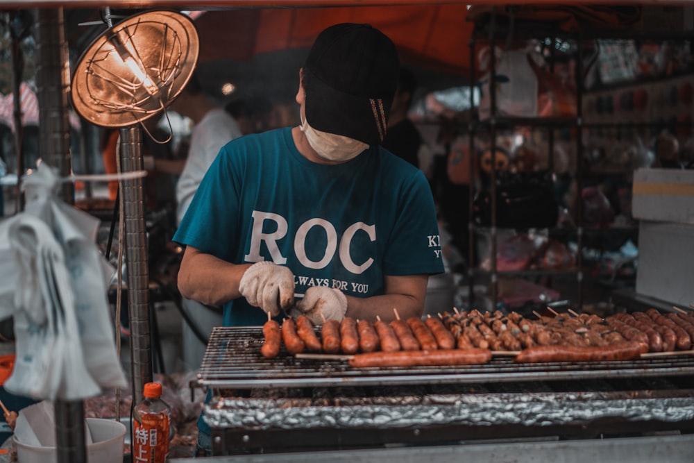 man in blue and white crew neck t-shirt standing in front of food stall