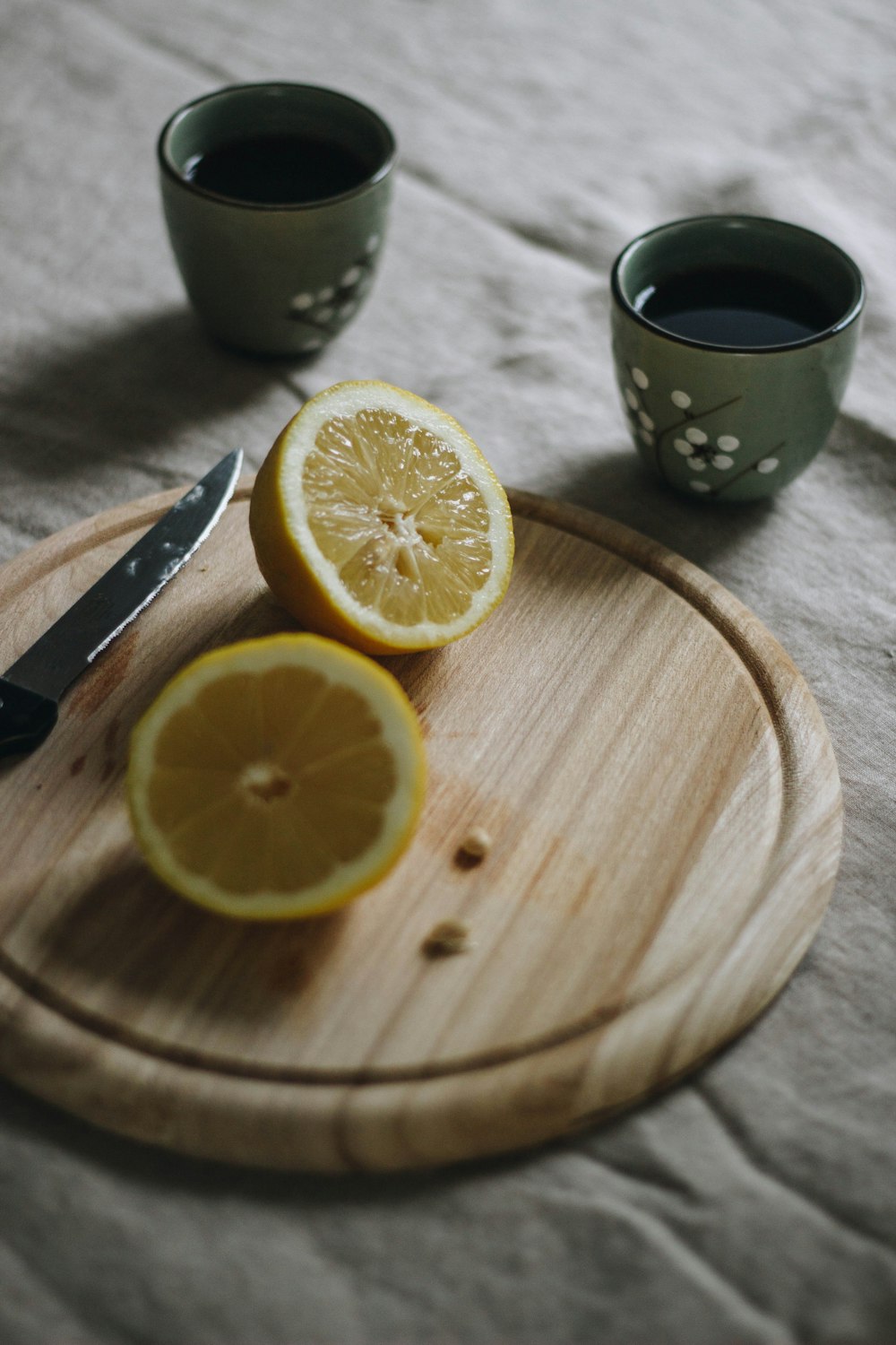 sliced lemon beside black ceramic mug on brown wooden table