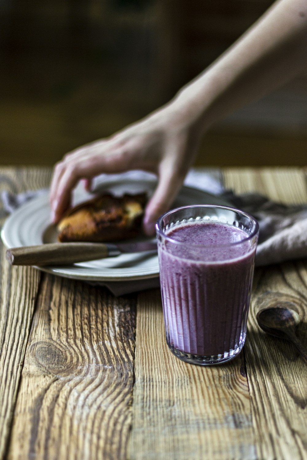 person holding clear drinking glass with purple liquid