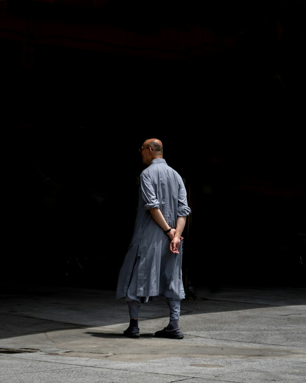 man in gray t-shirt and gray pants walking on gray concrete pavement