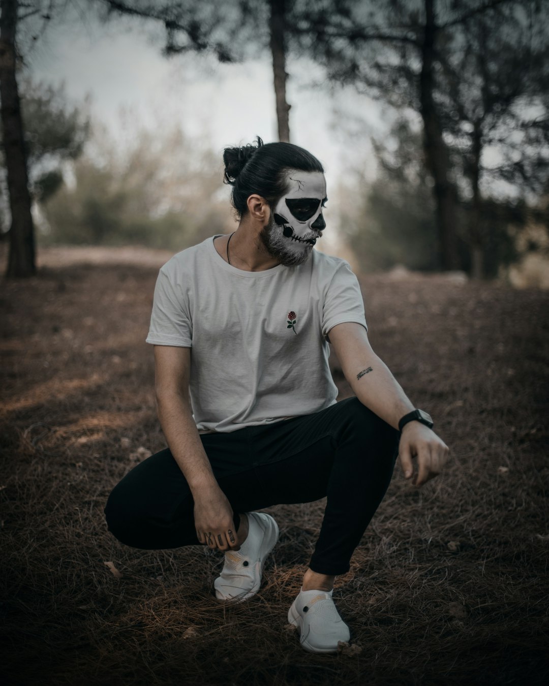 man in white crew neck t-shirt and black pants wearing black sunglasses sitting on brown