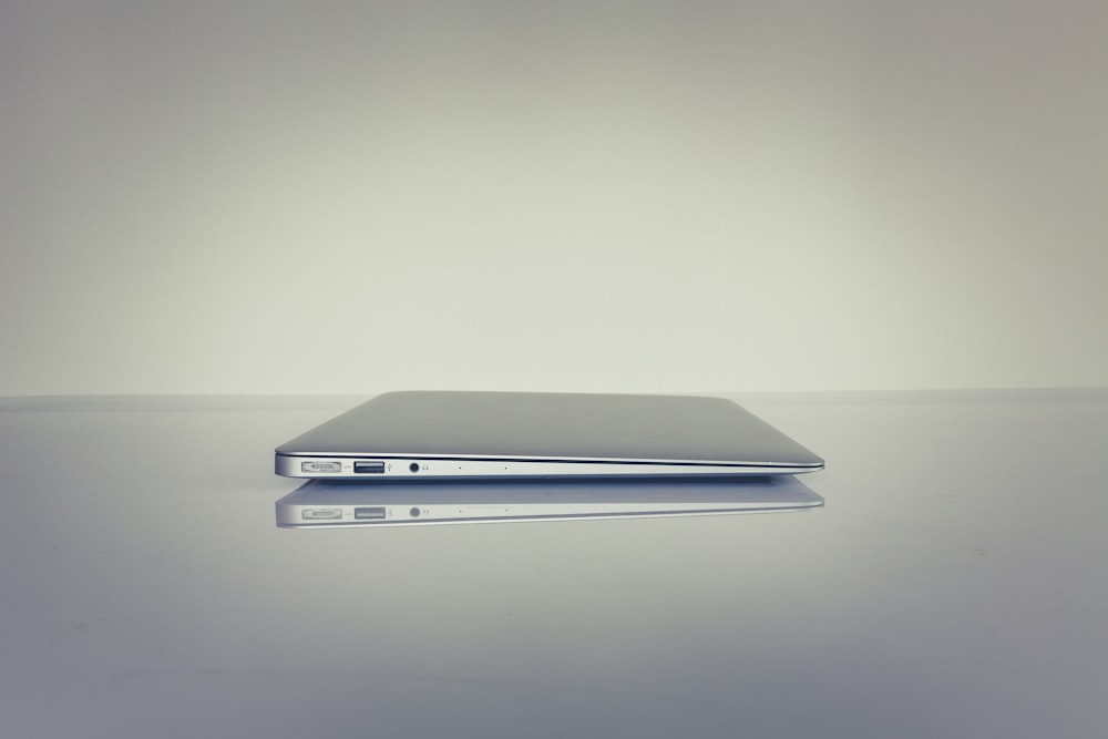 silver laptop computer on white table