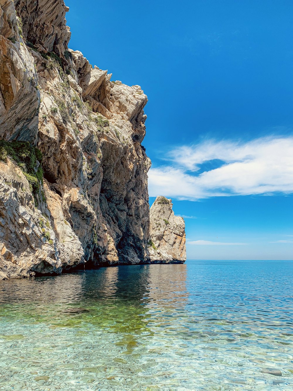 brown rock formation on blue sea under blue sky during daytime