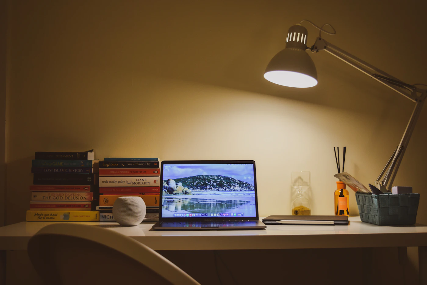 Laptop on a desk lit by a lamp in the evening
