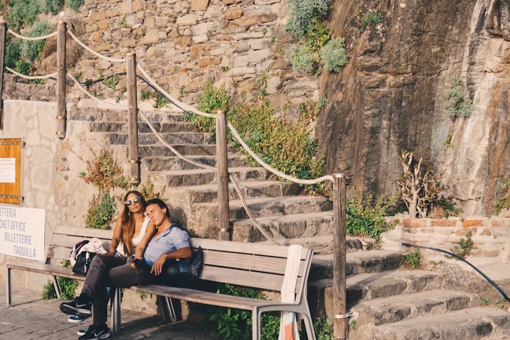 2 women sitting on brown wooden bench during daytime